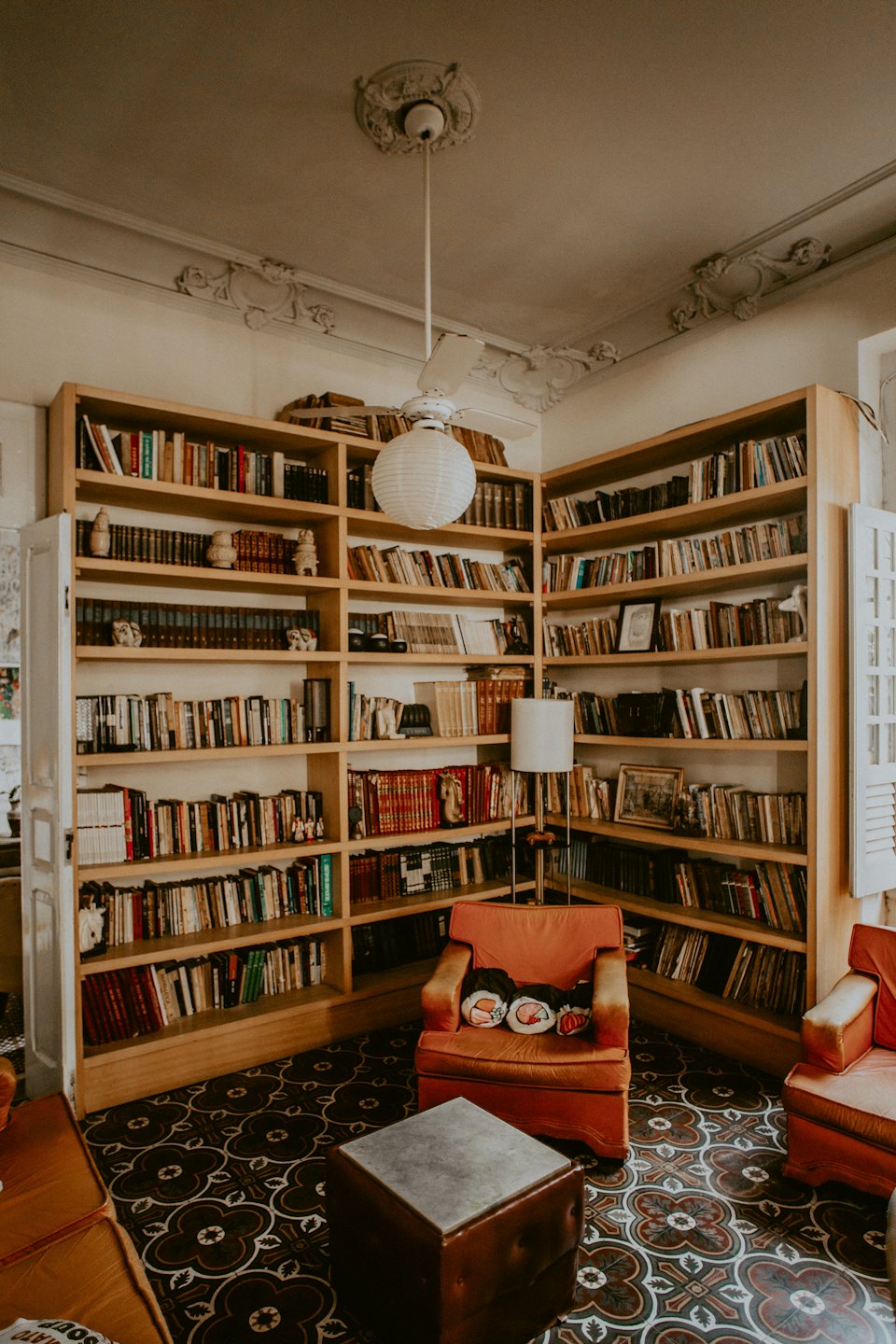 Home Accogliente sala lettura con due grandi librerie e una poltrona arancione.